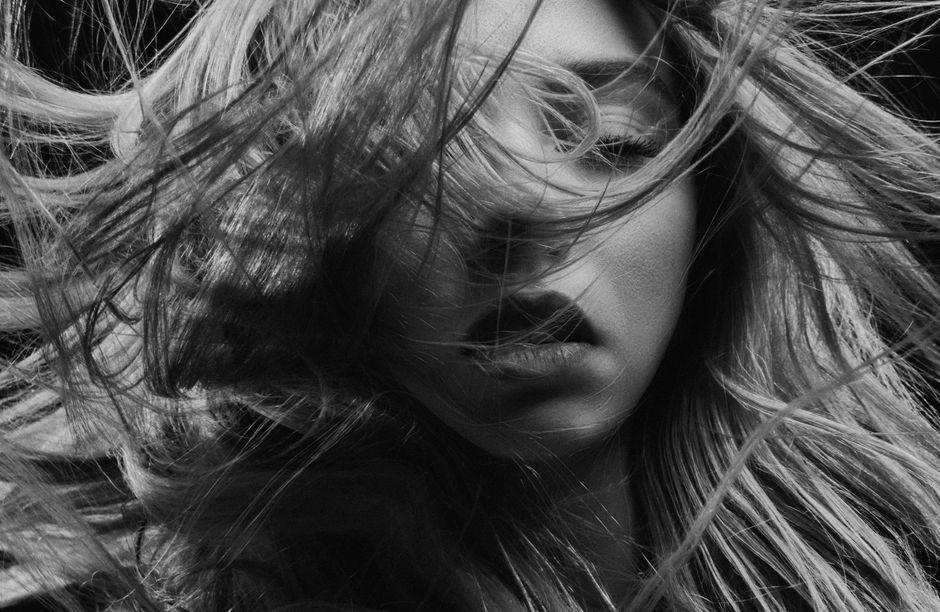 Dramatic black and white portrait of a woman with dynamic hair movement.