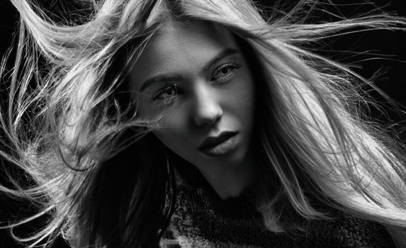 Artistic black and white portrait capturing an expressive woman's face with flowing hair.