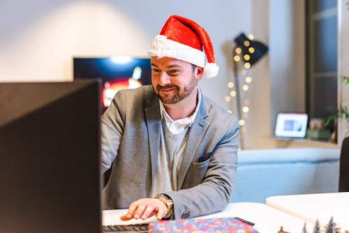 Bearded Man Wearing Santa Hat While Working