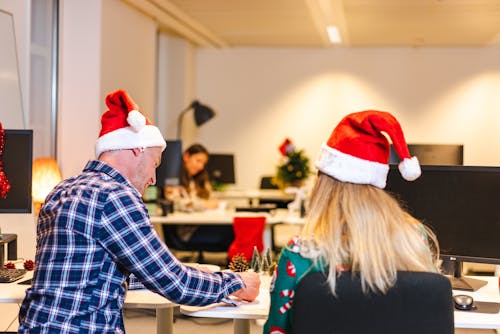 A Man and Woman in Santa Hats Working in an Office