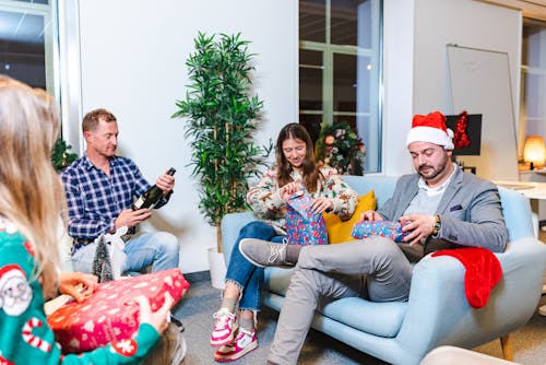 Men and Women Sitting and Holding Christmas Gifts