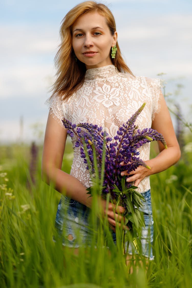 Woman Holding Flowers In A Field Of Tall Grass 