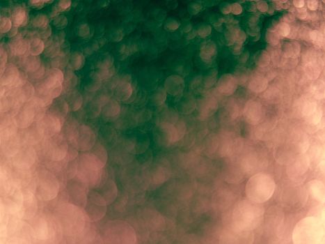 Blurred abstract background of green and peach bokeh lights.