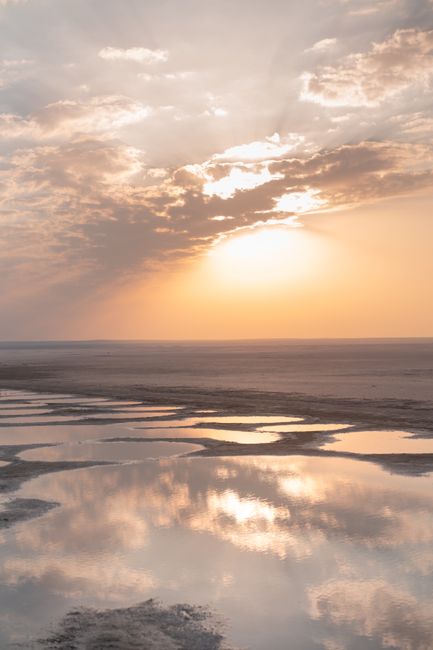Tranquil sunset casting warm light over reflective beach pools creating a serene landscape.