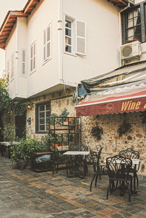Free Charming outdoor café with vintage decor, tables, chairs, and potted plants in a cozy setting. Stock Photo