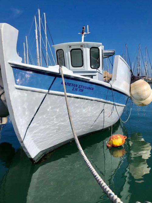 Free White fishing boat gently floating in a marina under a clear blue sky. Stock Photo