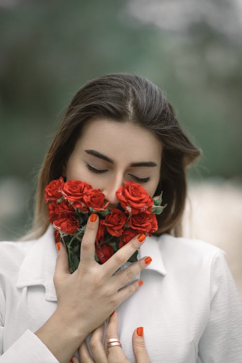 Close-Up Shot of a Beautiful Woman Holding Red Roses
