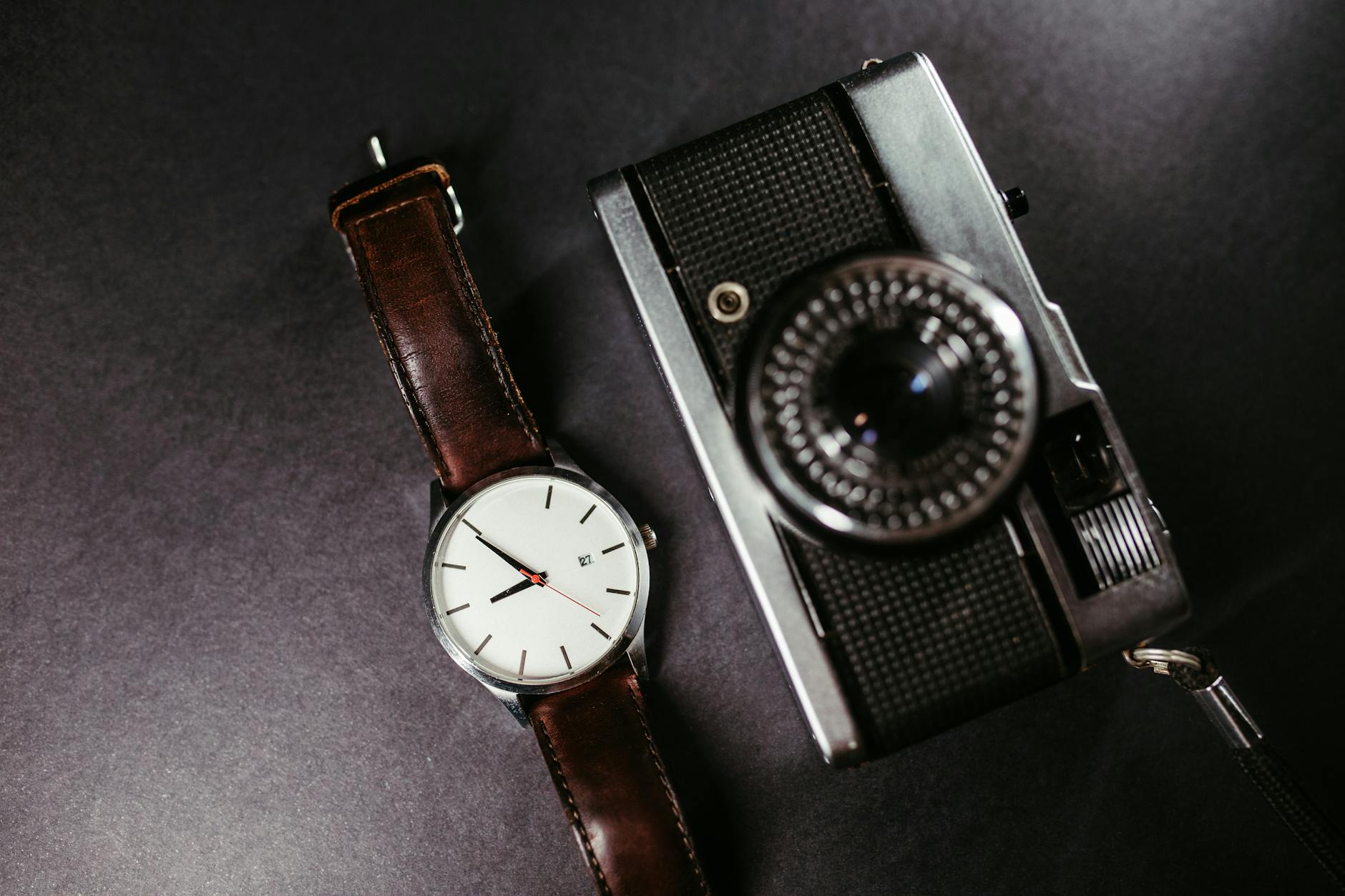 A close-up of a vintage camera and wristwatch with a leather strap