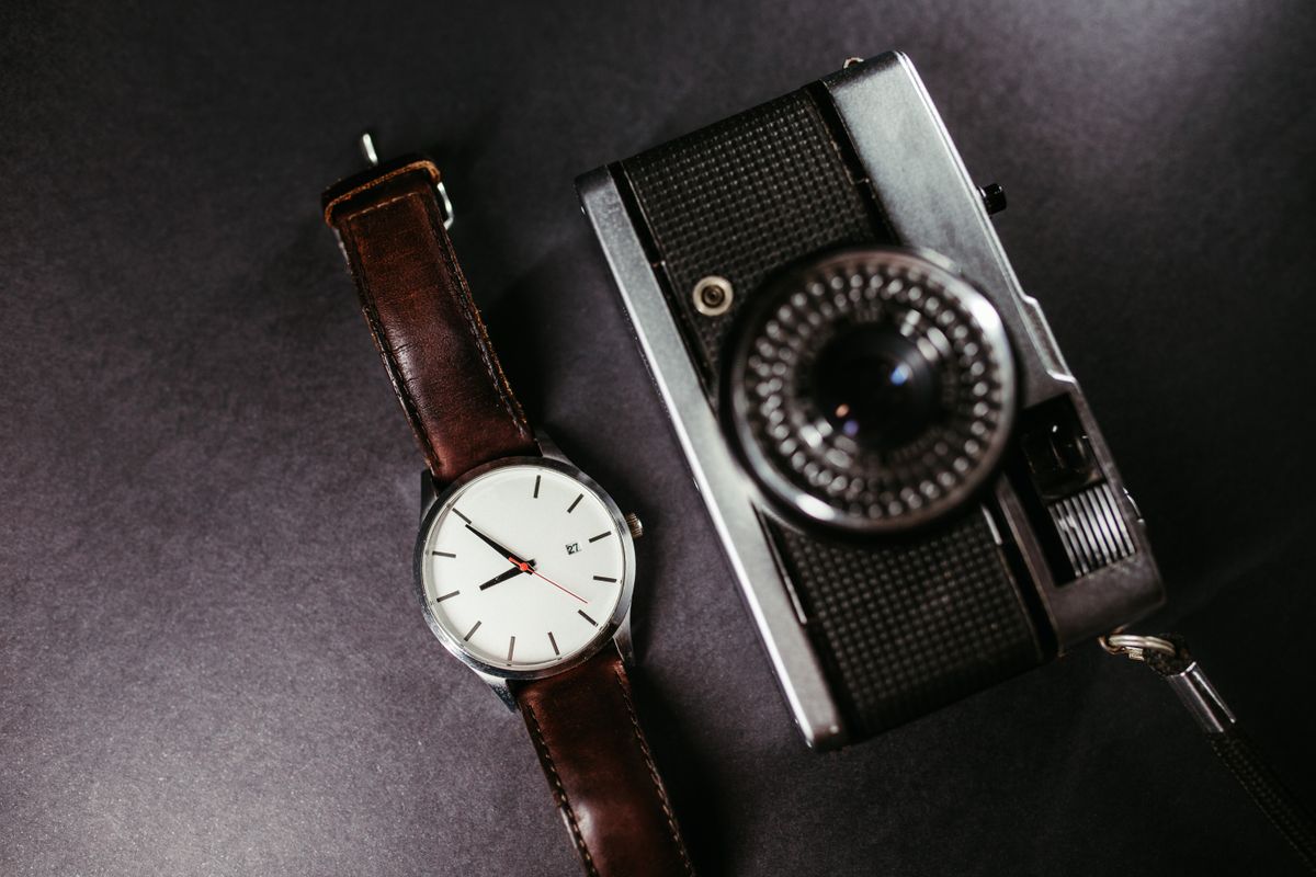 Cámara vintage junto a un reloj de pulsera, evocando el proceso de documentar cada pieza
