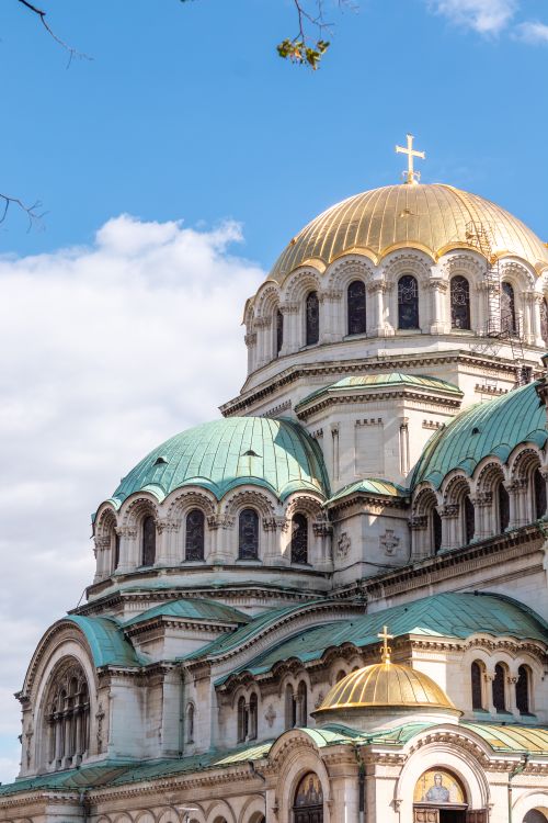 Free View of St. Alexander Nevsky Cathedral, Sofia with iconic domes against a vibrant blue sky and clouds. Stock Photo