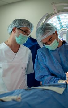 Surgeons wearing masks and gowns focus on performing a procedure in the operating theater.