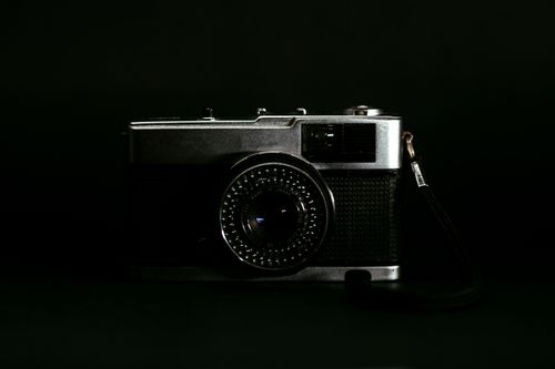 Free A vintage camera captured in a moody product shot with a black background. Stock Photo