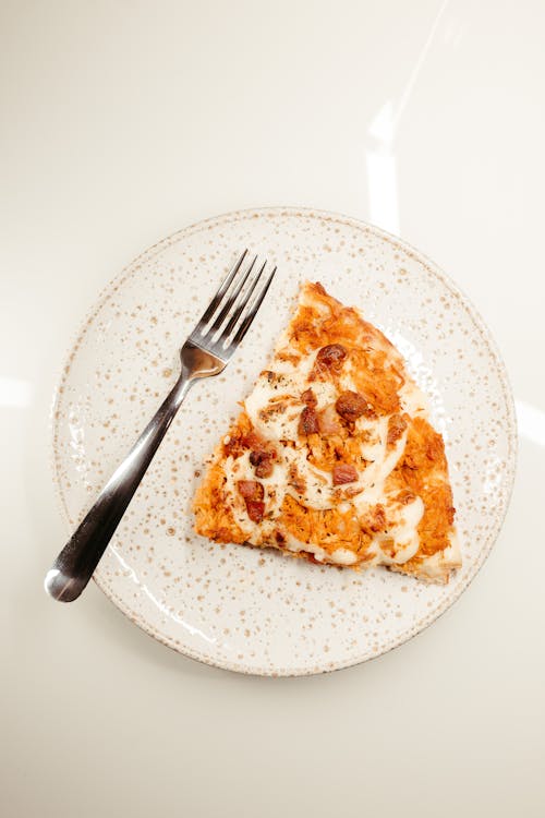 Free Slice of Pizza and Fork on Ceramic Plate Stock Photo