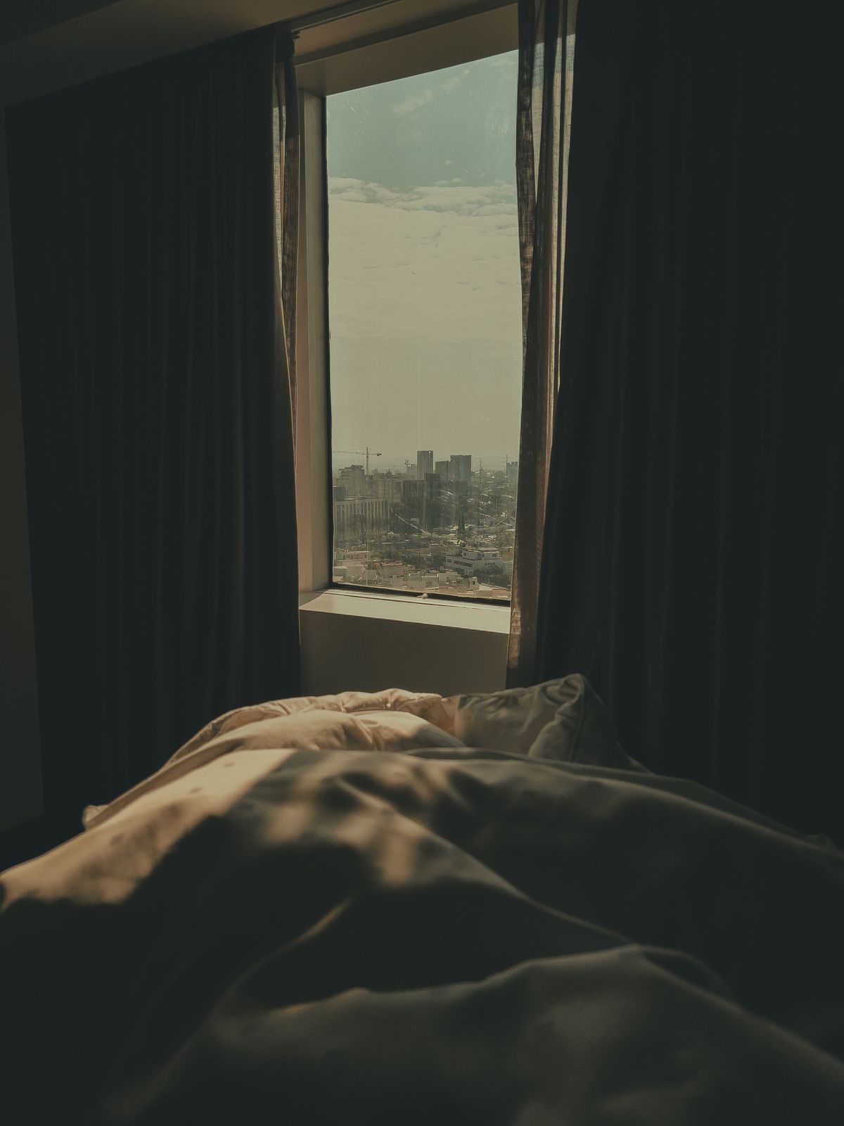Dark, cool bedroom with curtains framing a window