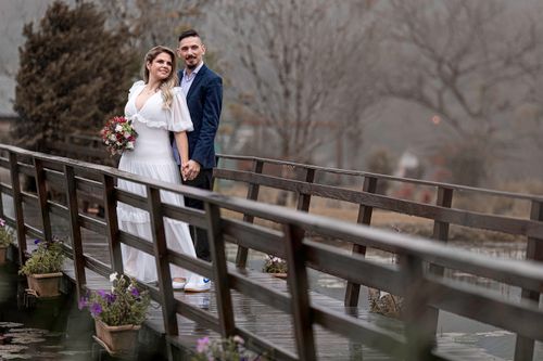 Free Bride and groom holding hands on a wooden bridge, showcasing love and elegance. Stock Photo