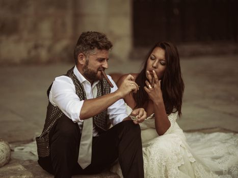 A couple sitting outdoors, enjoying cigars in a relaxed and intimate setting.