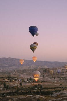 Stunning view of hot air balloons floating over Cappadocia's unique landscape at sunrise.