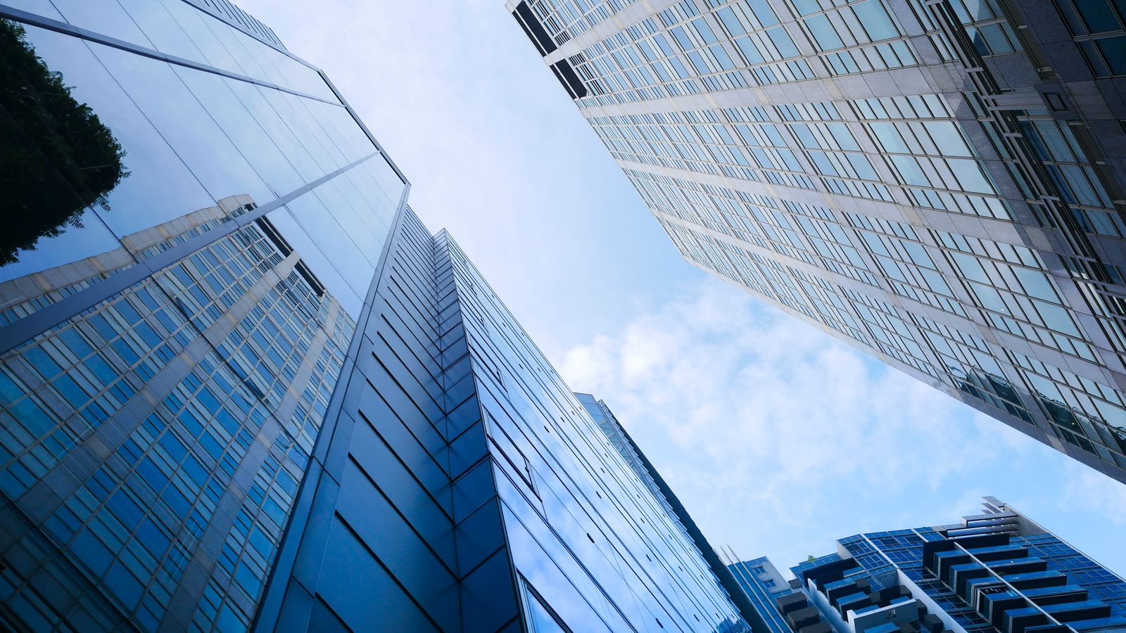 Low angle view of modern skyscrapers reflecting the sky, showcasing urban architecture.
