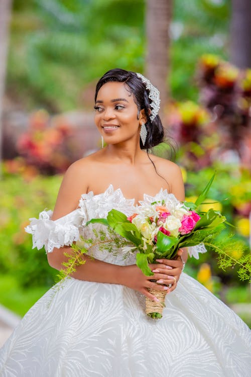 A Woman in Wedding Gown Holding Bouquet of Flowers