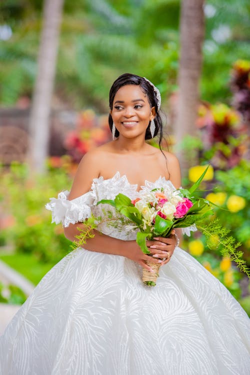 Smiling Woman in White Wedding Dress Holding Bouquet of Flowers