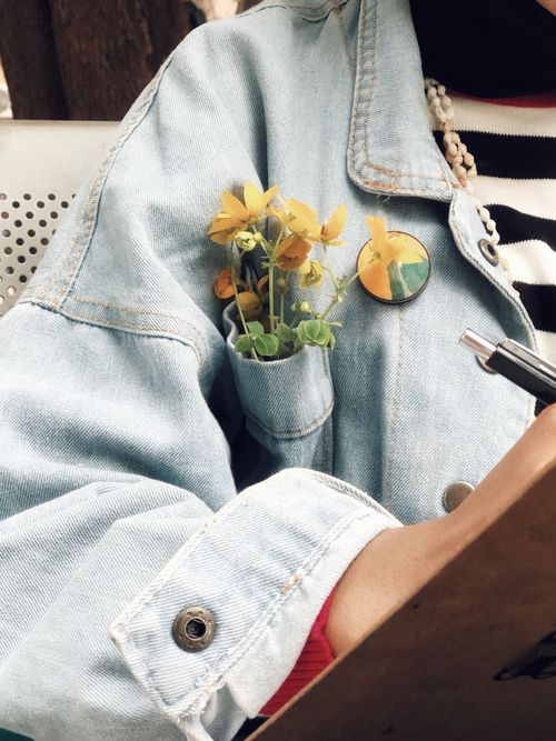 Free Close-up of a denim jacket with yellow flowers in the pocket, offering a stylish and vibrant look. Stock Photo