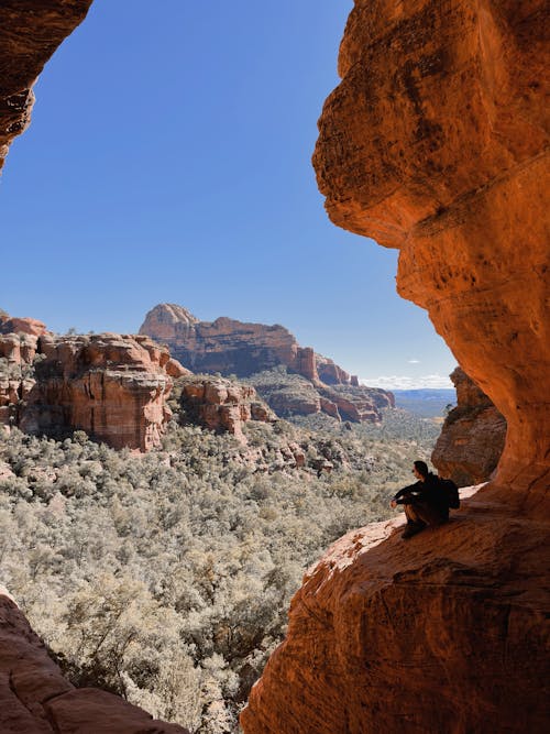 Free A Man Sitting on a Rock Formation Stock Photo