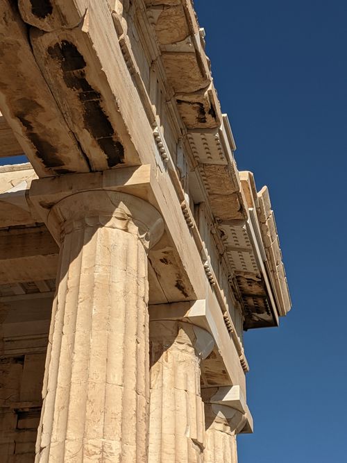 Free Detailed view of classical Greek temple columns and architectural elements under a clear blue sky. Stock Photo