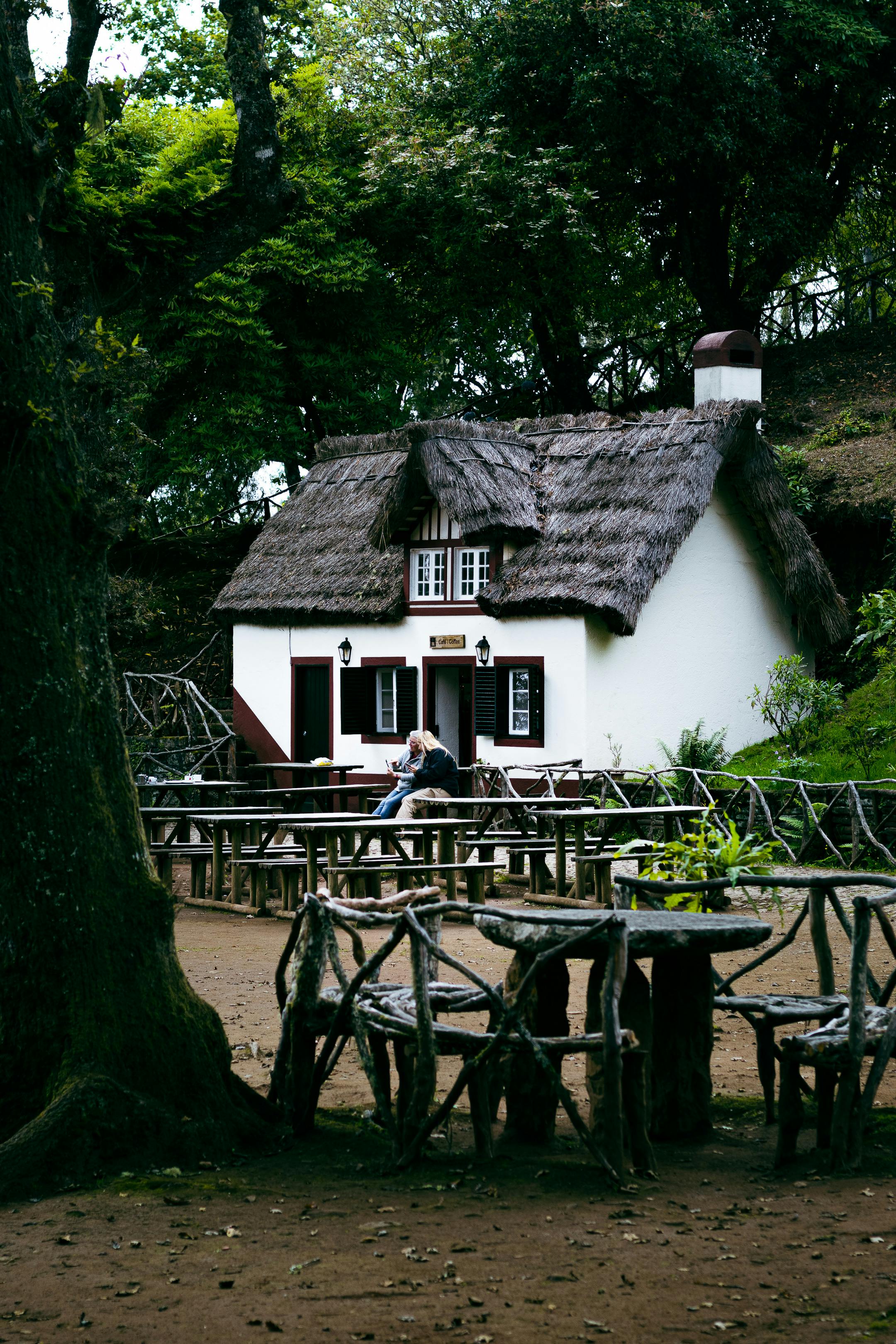 Cozy thatched cottage with rustic outdoor seating in Santana, Madeira forest.