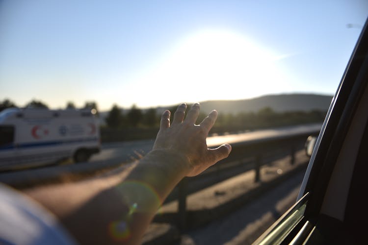 Person With Arm And Hand Reaching Out From A Vehicle Window