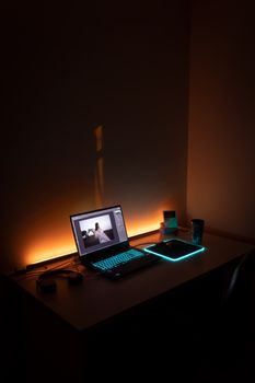 A dimly lit workspace featuring a glowing laptop and mouse pad in İzmir, Turkey.
