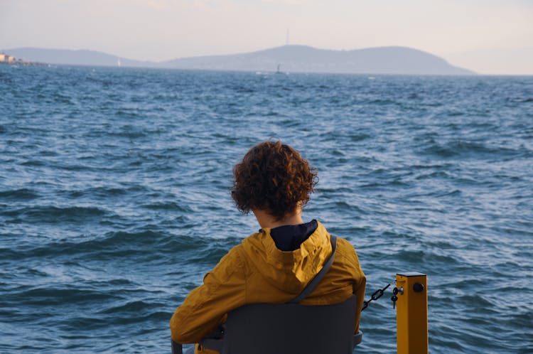 Woman Sitting On Chair On Sea Shore