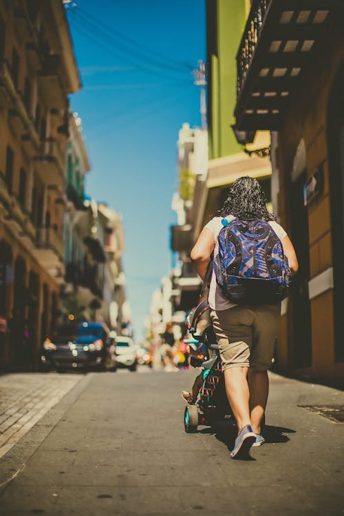 Woman With Backpack Walking While Pushing a Baby Stroller 