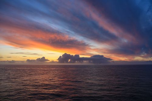 Free Stunning sunset over the ocean with vivid colors and dramatic clouds. Stock Photo