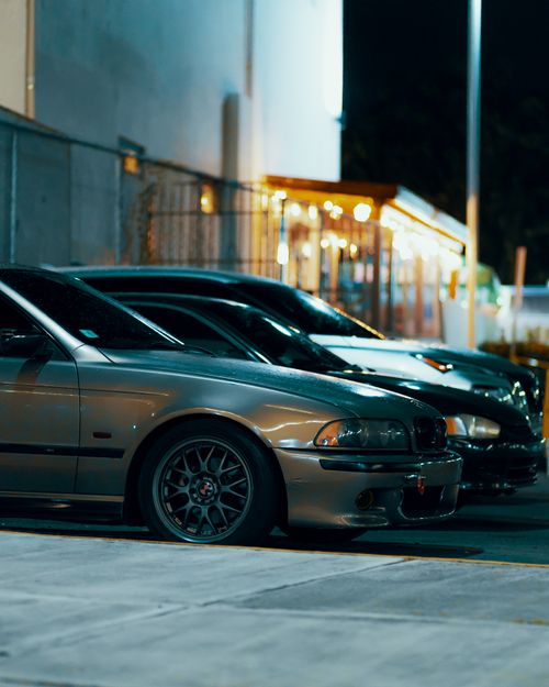 Free Street scene of parked cars at night in an urban setting with warm lighting. Stock Photo