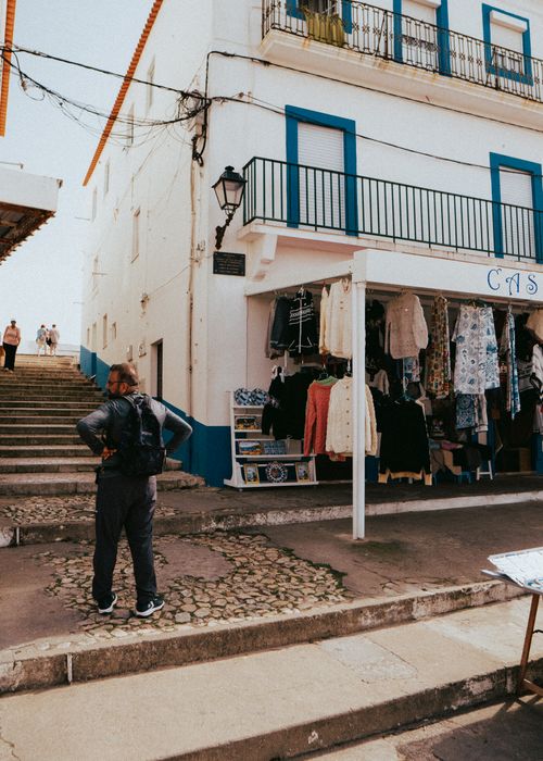 Free Tourists explore a charming street in Nazaré, Portugal, with a clothing store and historic architecture. Stock Photo