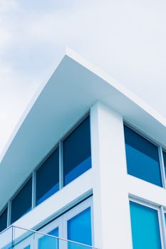Stylish modern building corner with white walls and blue glass windows in bright light.