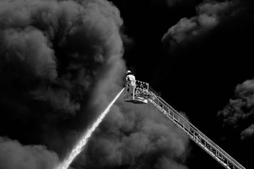 Free Firefighter on a Crane Extinguishing a Large Fire  Stock Photo
