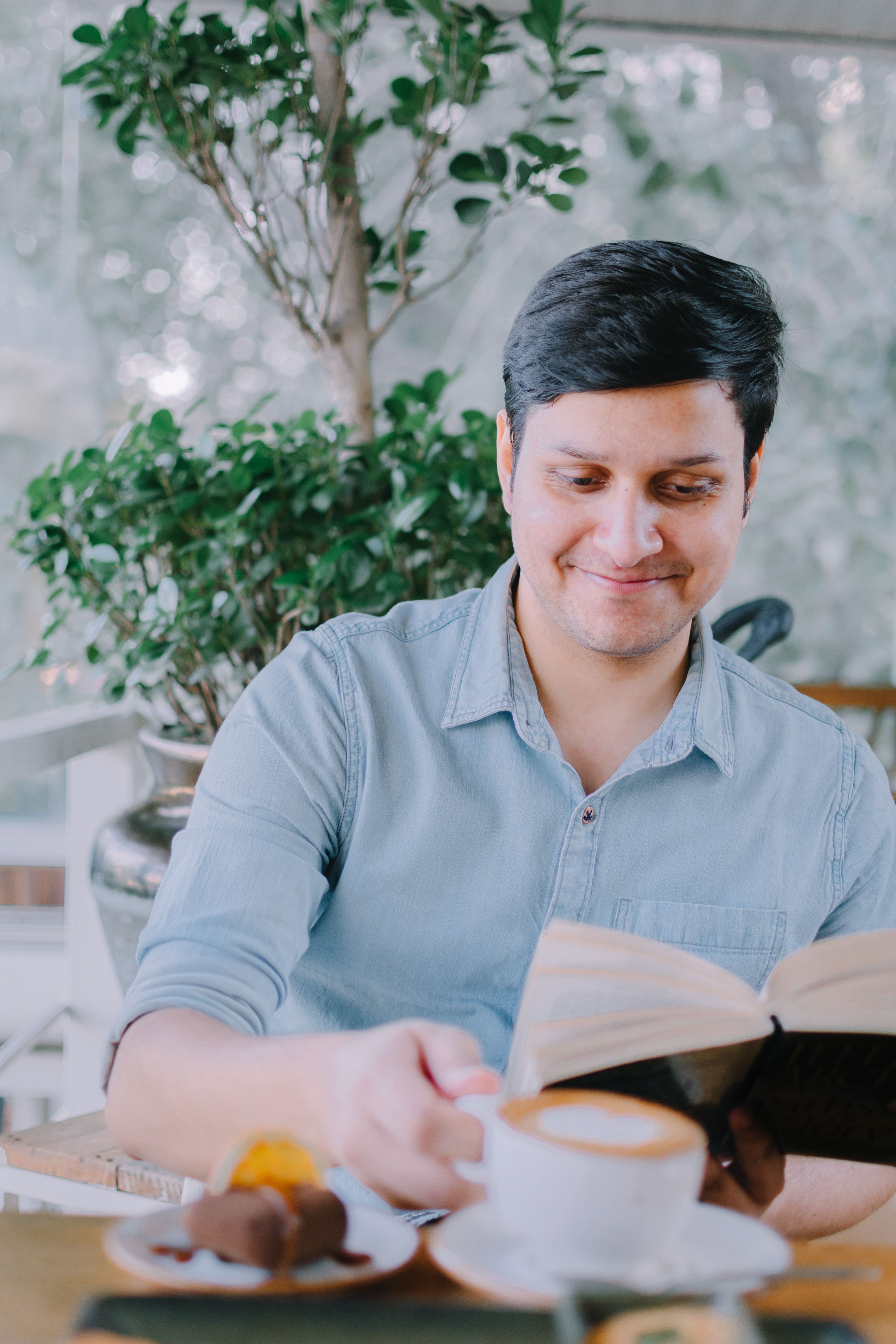 Man enjoying coffee and reading a book in a cozy café, showcasing relaxation.