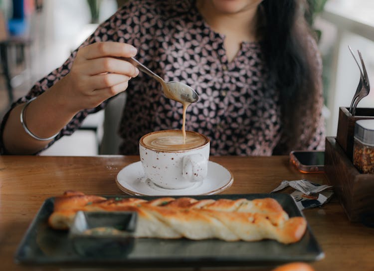 Woman Drinking Coffee At Table In Cafe