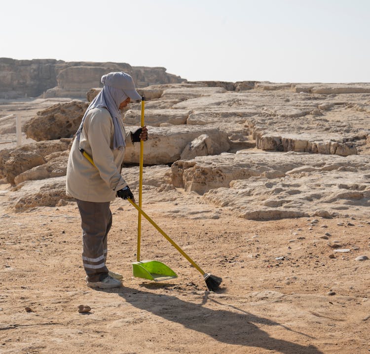 Woman Sweeping Trash On A Beach