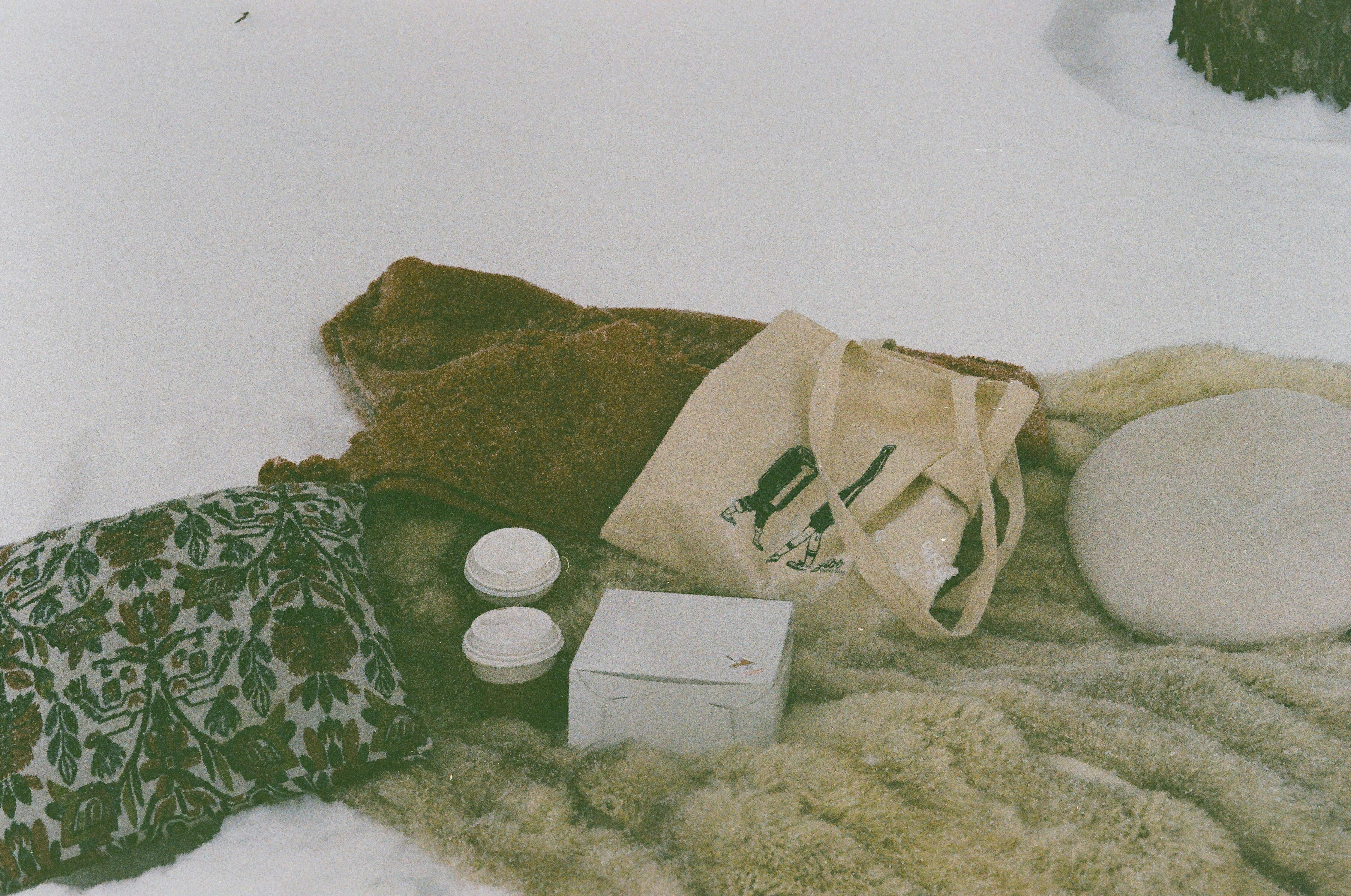 cups of coffee beside a box and a tote bag on a faux fur