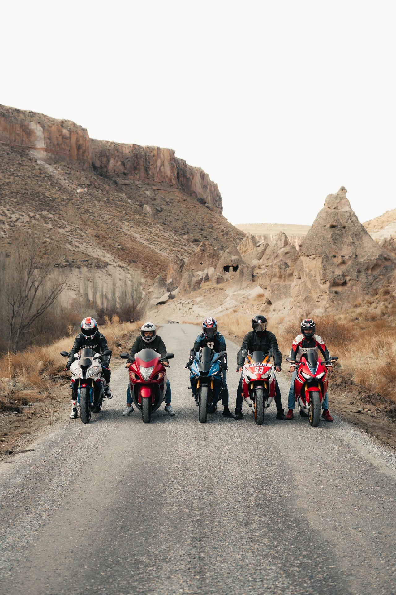 Five motorcyclists ride through a rugged desert canyon road