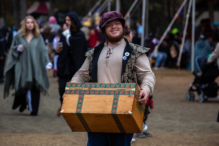 Smiling Man In Medieval Costume Carrying Chest