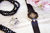 特写：奢华黑色珠宝与镶有粉色花朵的木制表面手表