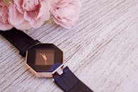 一块豪华手表的特写位于乡村木桌上的粉红玫瑰旁，散发着优雅与浪漫