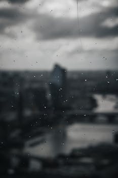 Blurry view of London's skyline through a window with raindrops, capturing a moody atmosphere.
