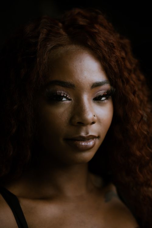 Free Stunning portrait of a woman showcasing elegant makeup and curly hair in soft lighting. Stock Photo