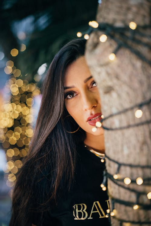 Brunette Woman Face behind Tree with Lights
