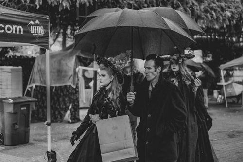 Free Three individuals in gothic costumes under umbrellas at an outdoor festival. Stock Photo