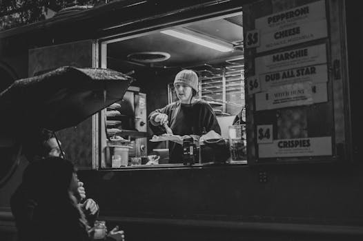 Black and white photo of a street food vendor serving customers at night.